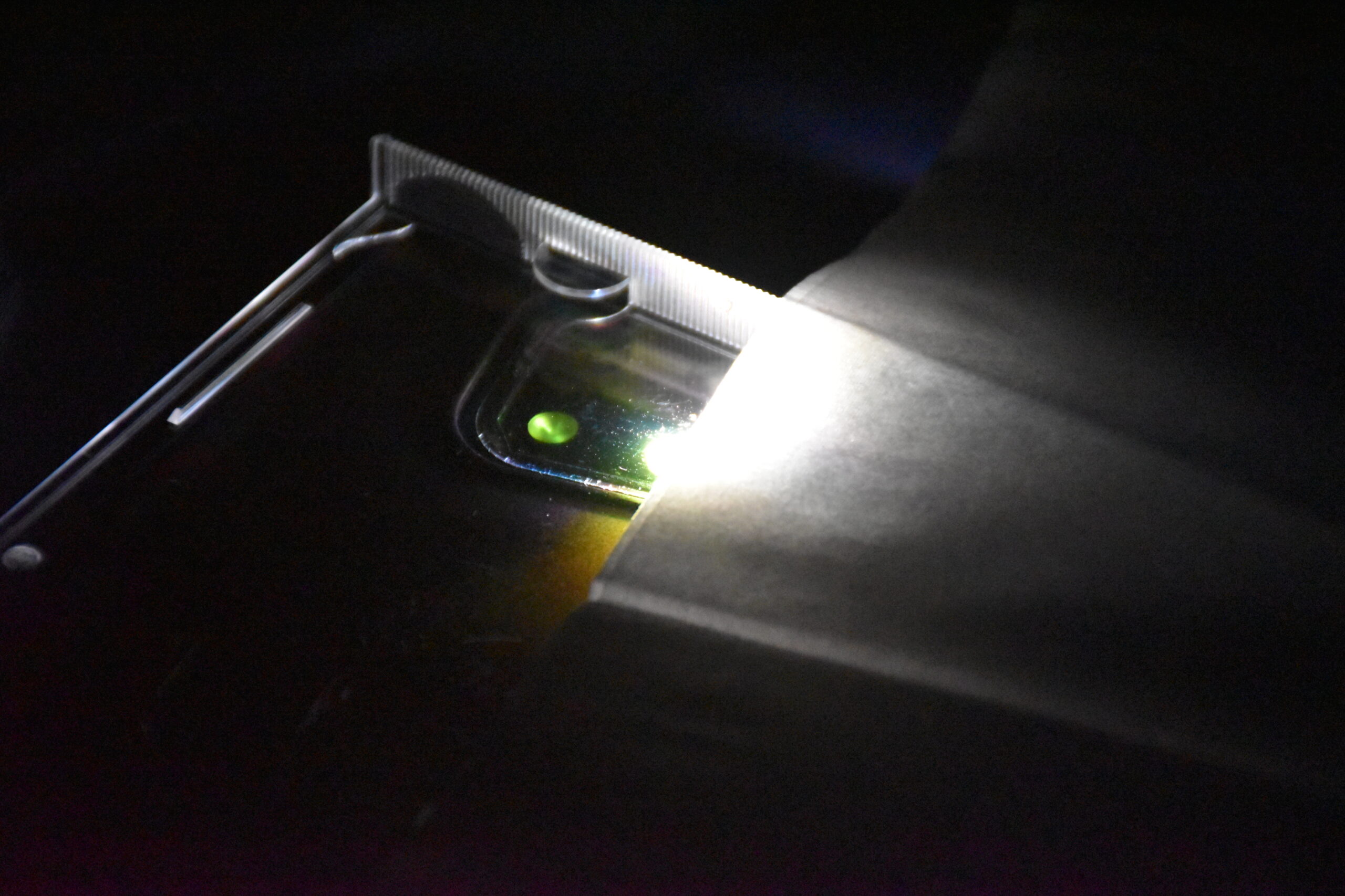 Green LED Light from my phone under a CD case. The LED is partially obscured by a Tissue, which seems to be illuminated in white.